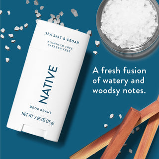 Native deodorant with text saying "A fresh fusion of watery and woodsy notes", styled with grains of sea salt and wood sticks 
