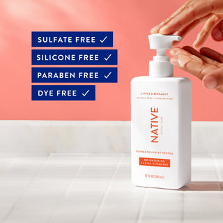 Hand using Native Brightening Facial Cleanser pump, with text listing sulfate-free, silicone-free, paraben-free, and dye-free claims