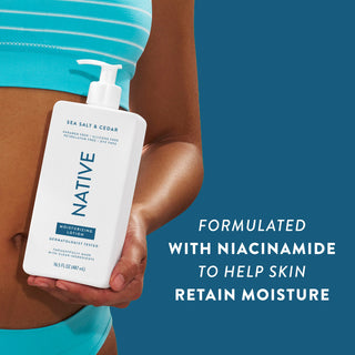 Woman holding Native Sea Salt & Cedar Moisturizing Lotion bottle with text reading "Formulated with niacinamide to help skin retain moisture"
