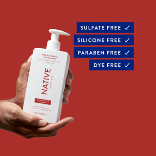 Hand holding Native Warm Cider & Cinnamon Moisturizing Shampoo bottle with text reading “Sulfate free, silicon free, paraben free, dye free”