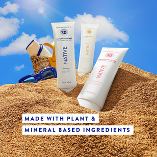 Three tubes of Native Mineral Suncare Daily Body Sunscreen in sand with a beach bag in the background 